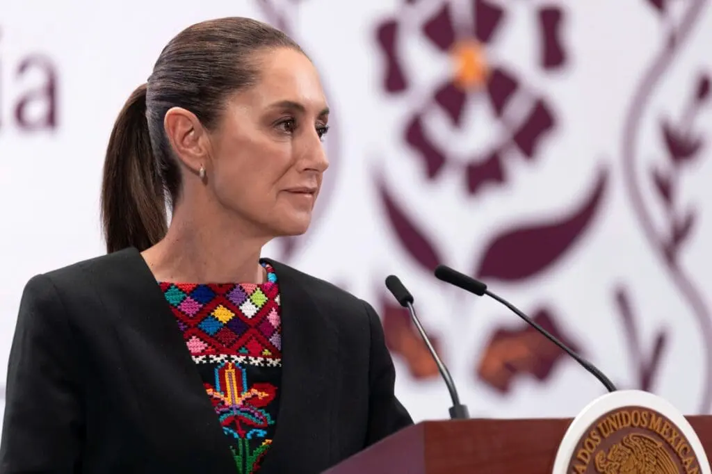 Woman speaking at a podium, patterned attire.