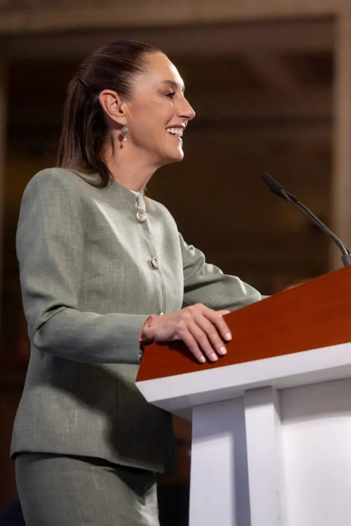 Woman speaking at a podium, smiling broadly.
