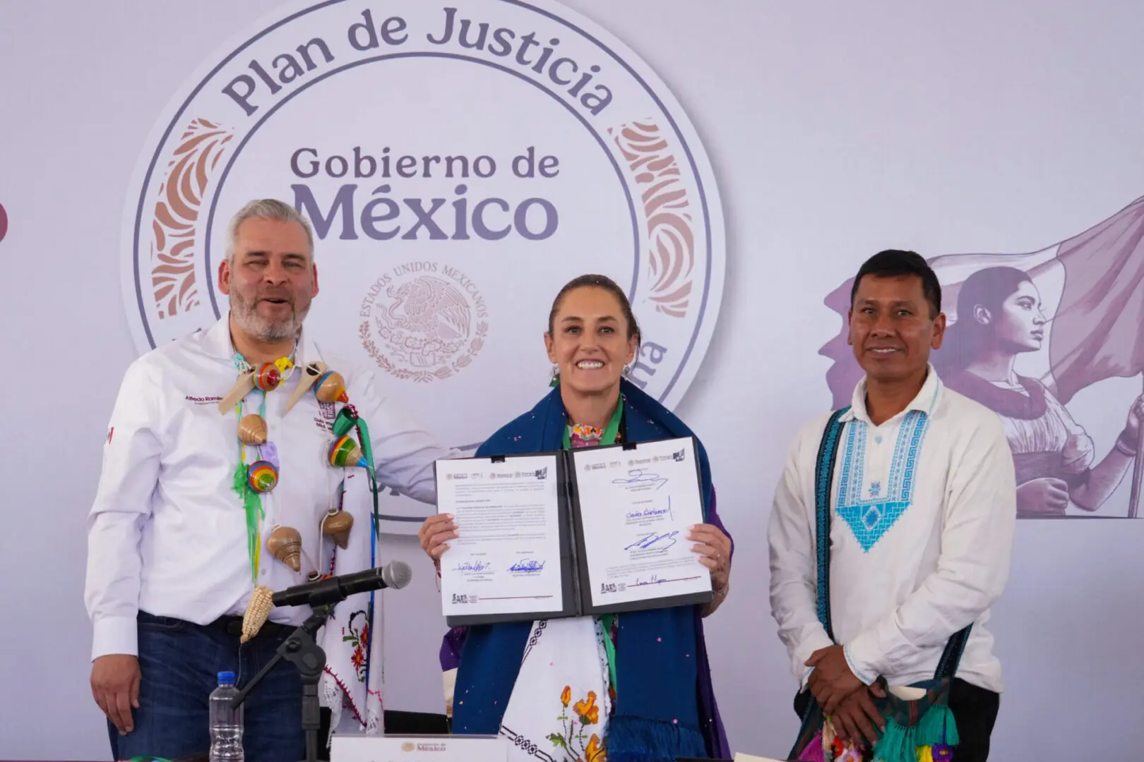 Three people holding documents, smiling at event.
