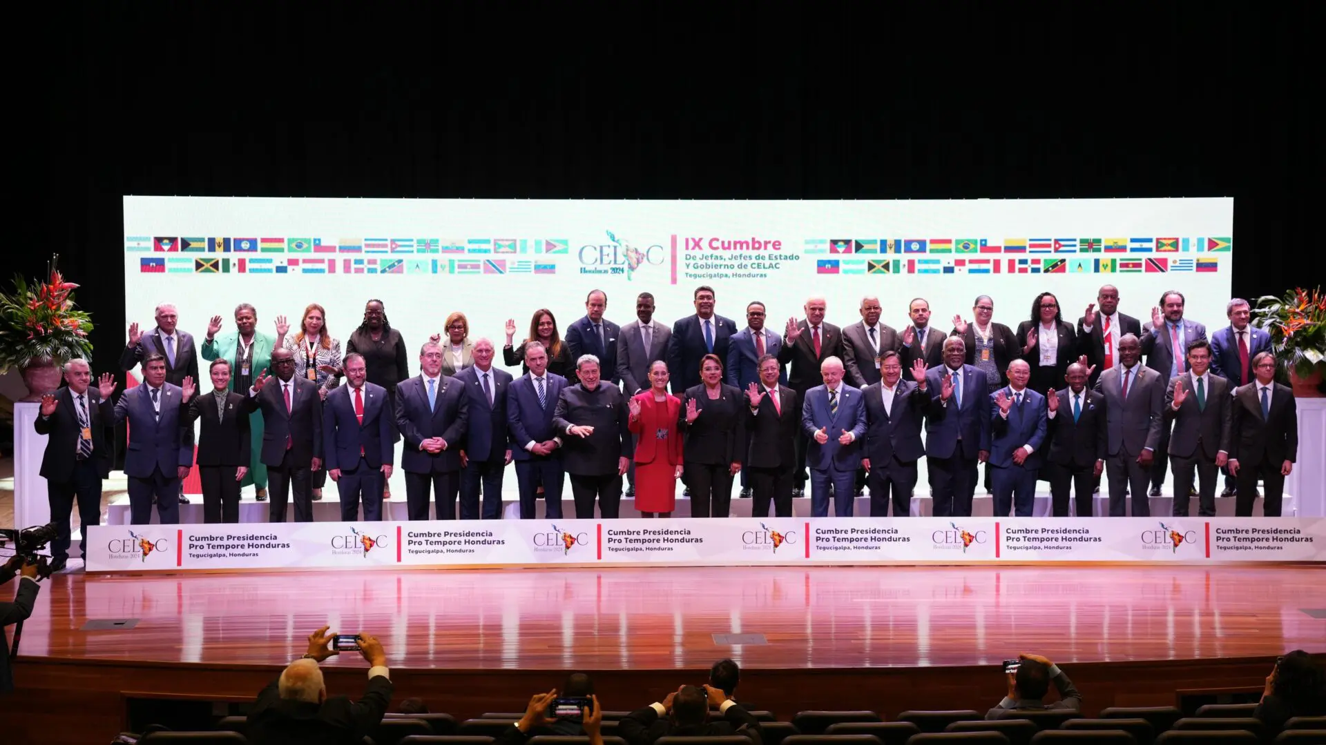 Group photo of conference attendees on stage.