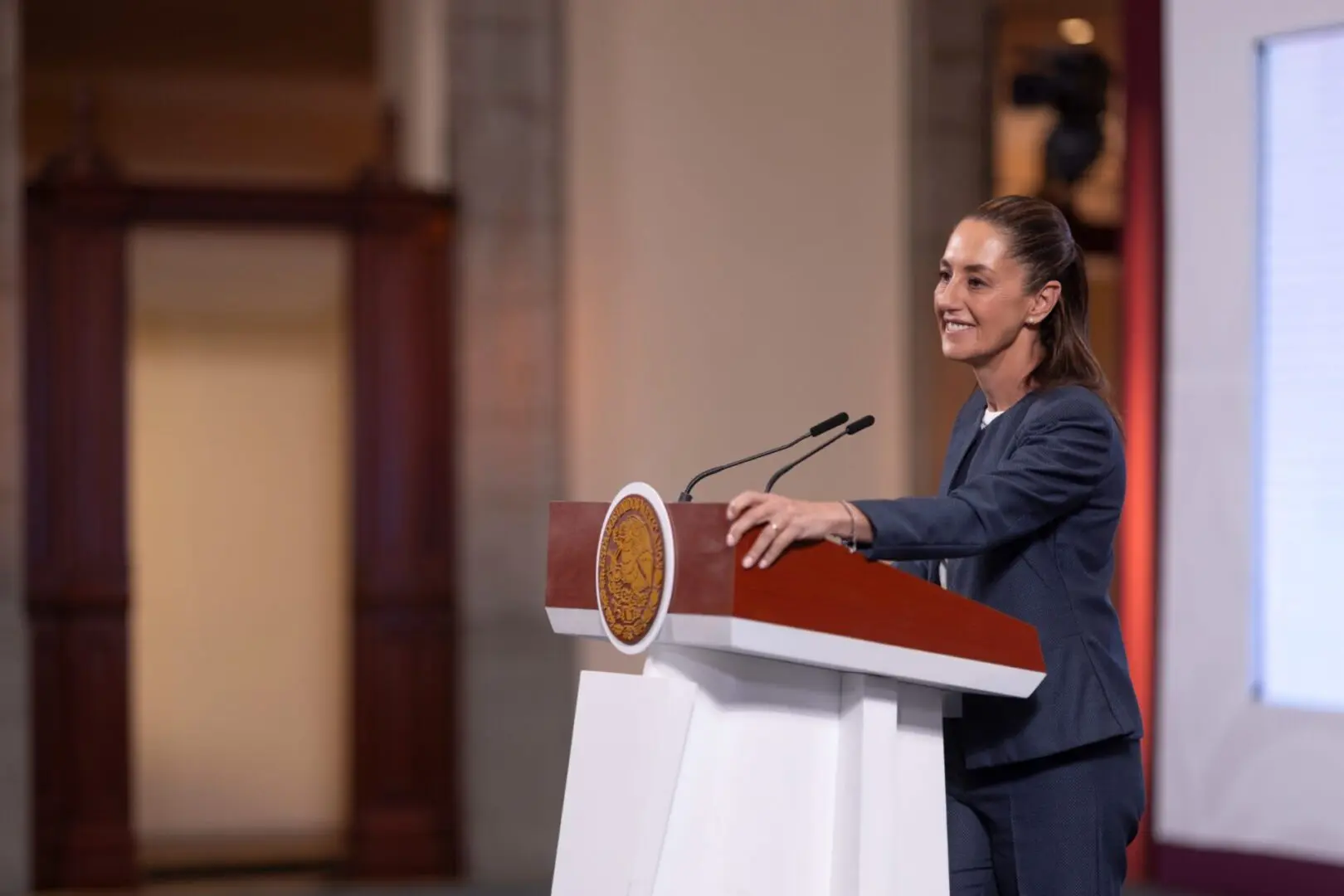 Woman speaking at podium in formal setting.