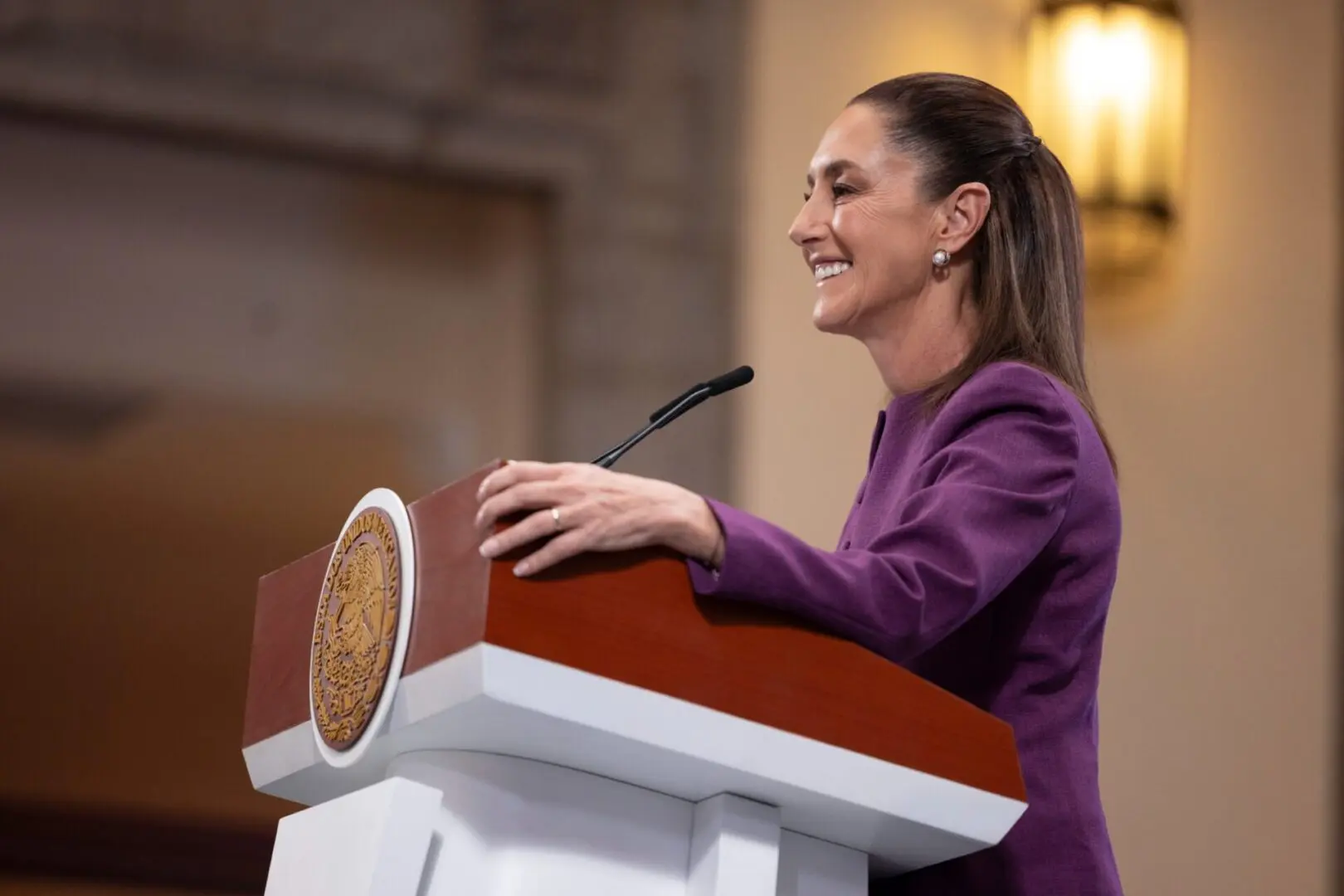 Woman in purple blazer speaking at podium