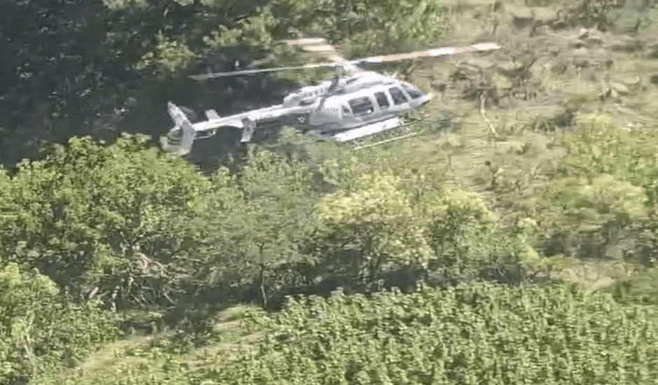 Helicopter flying over lush green landscape.
