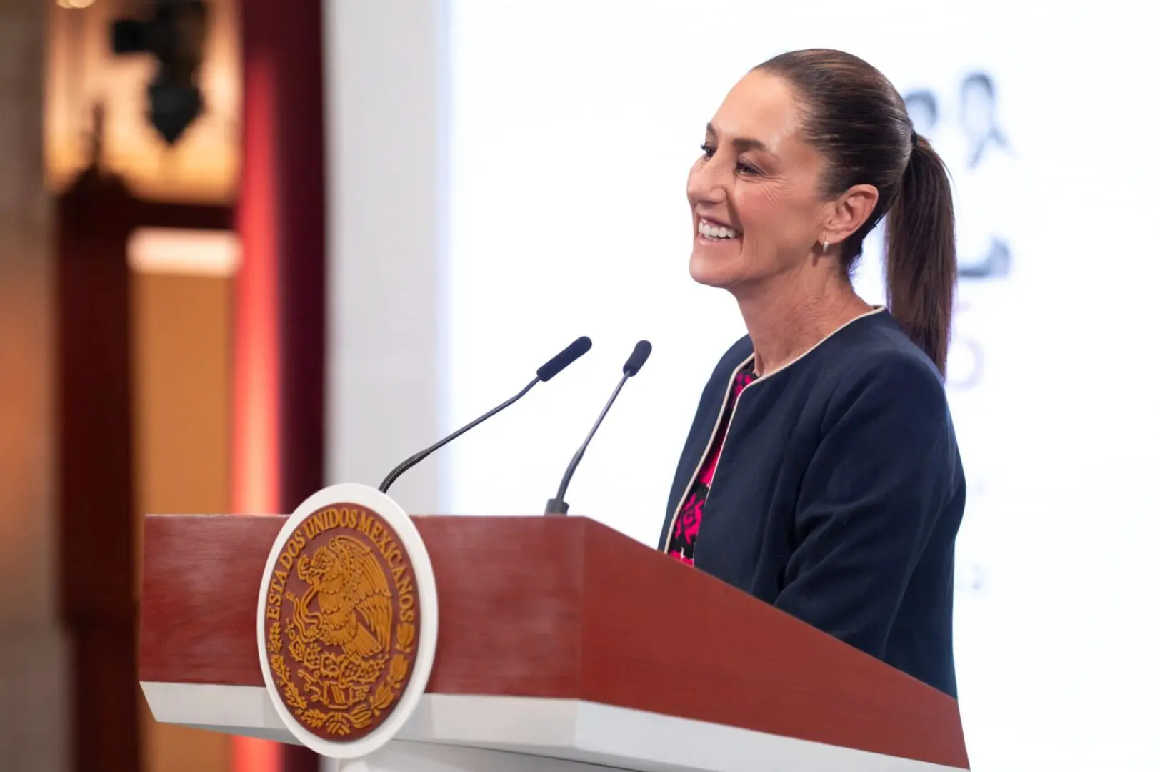Smiling female speaker at official podium