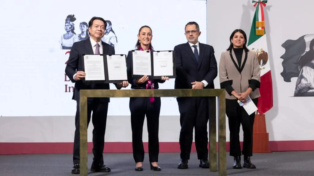 Four people standing behind a table, three holding certificates.