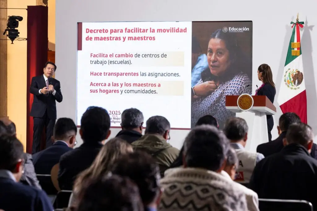 A woman presenting a slide to an audience in a seminar.