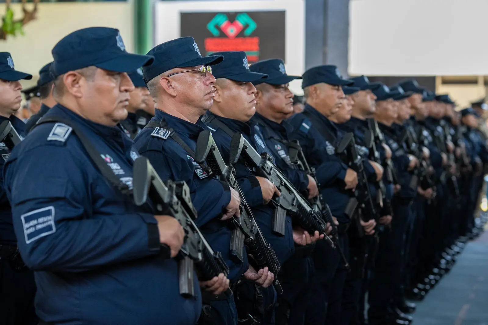A line of uniformed police officers holding rifles in formation.