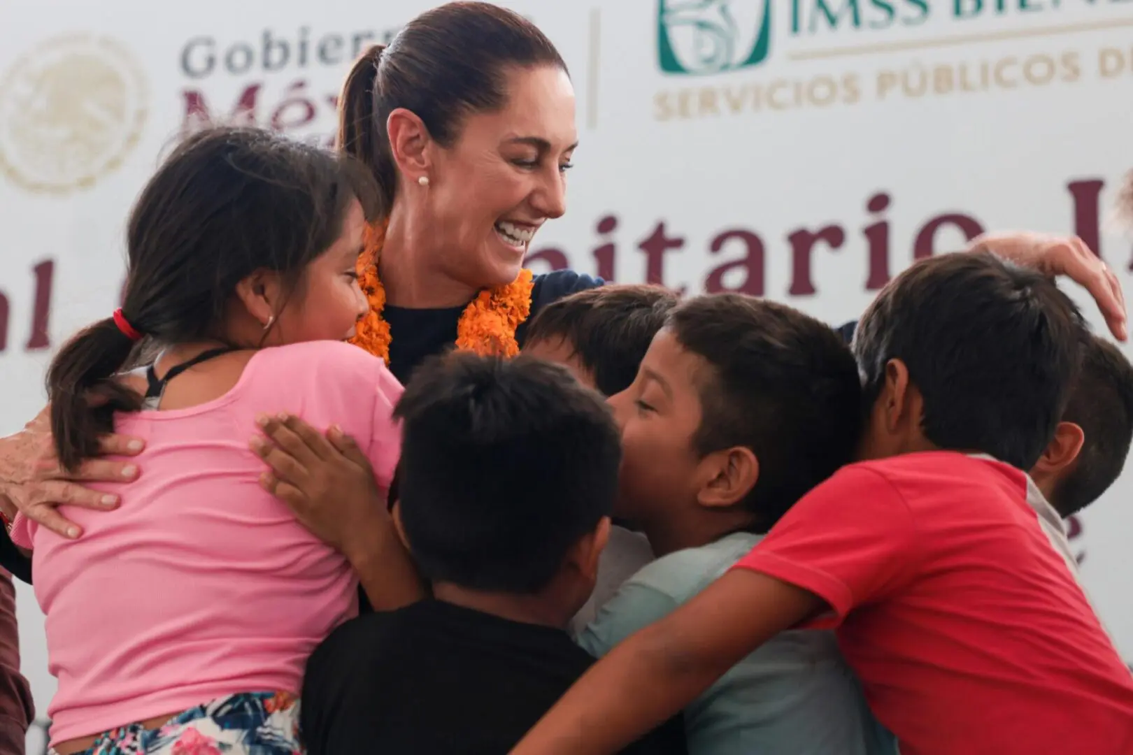 Woman hugging a group of smiling children.