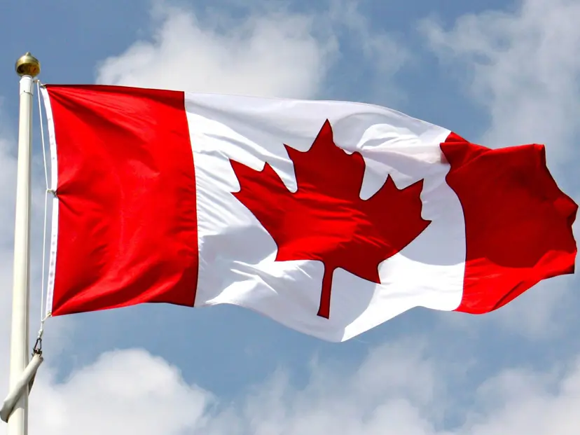 Canadian flag waving against a cloudy sky.