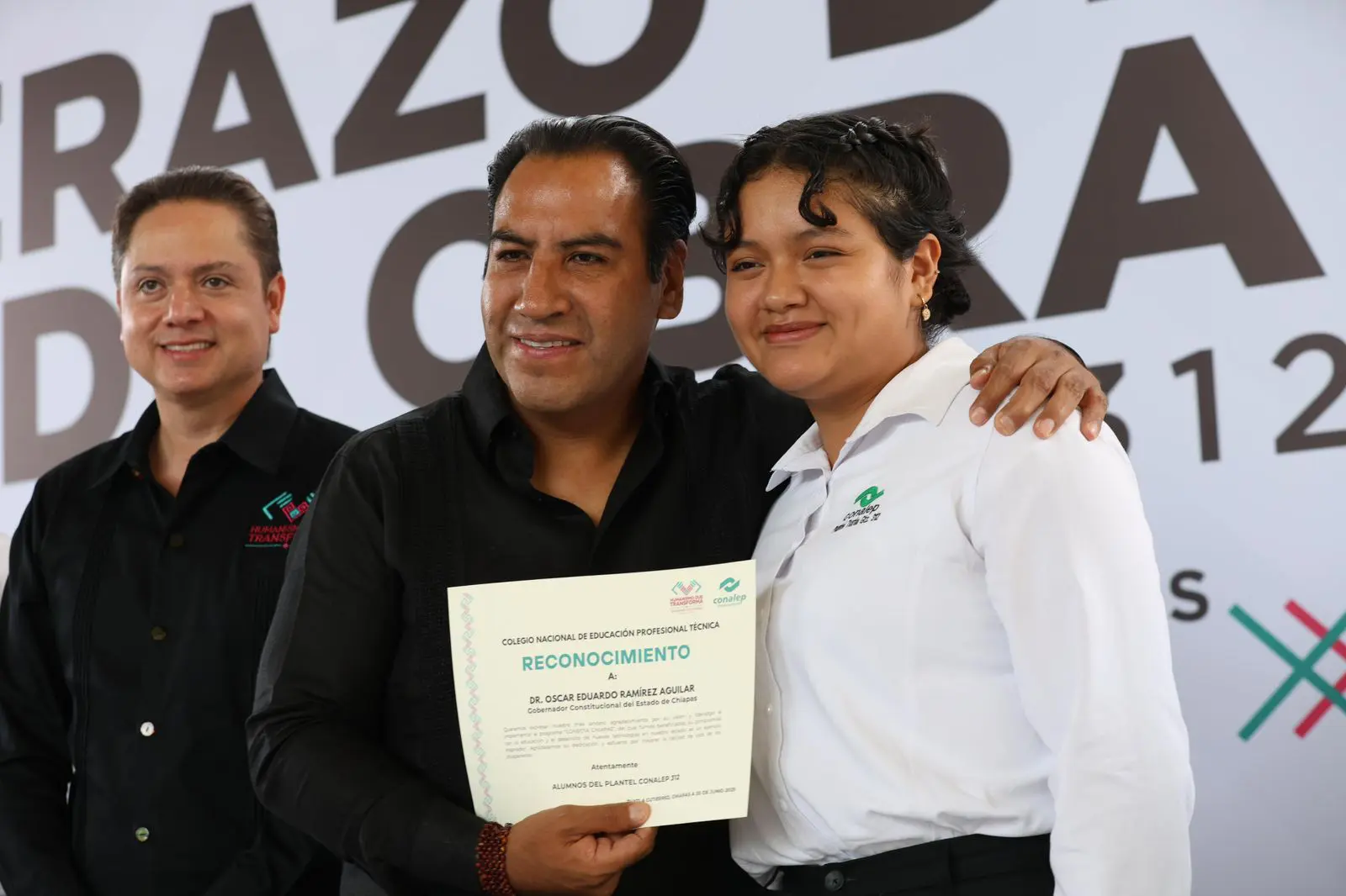 Three people posing with a certificate.