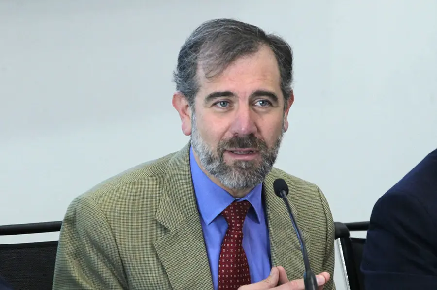 Man speaking at a microphone, wearing suit.