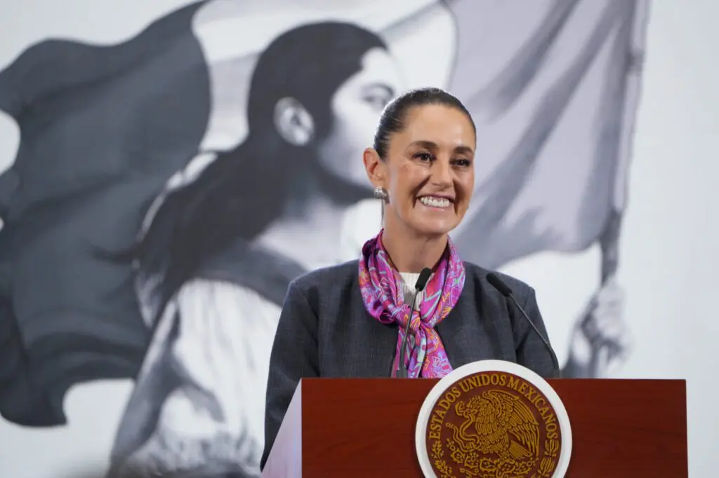 Smiling woman speaking at podium with Mexican seal