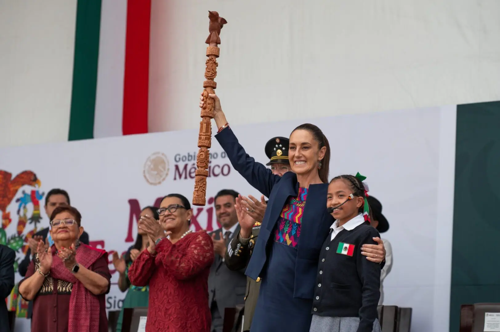 La mandataria celebra siete siglos de Tenochtitlan levantando un bastón ceremonial junto a una niña
