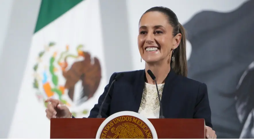 Woman speaking at podium with Mexican flag