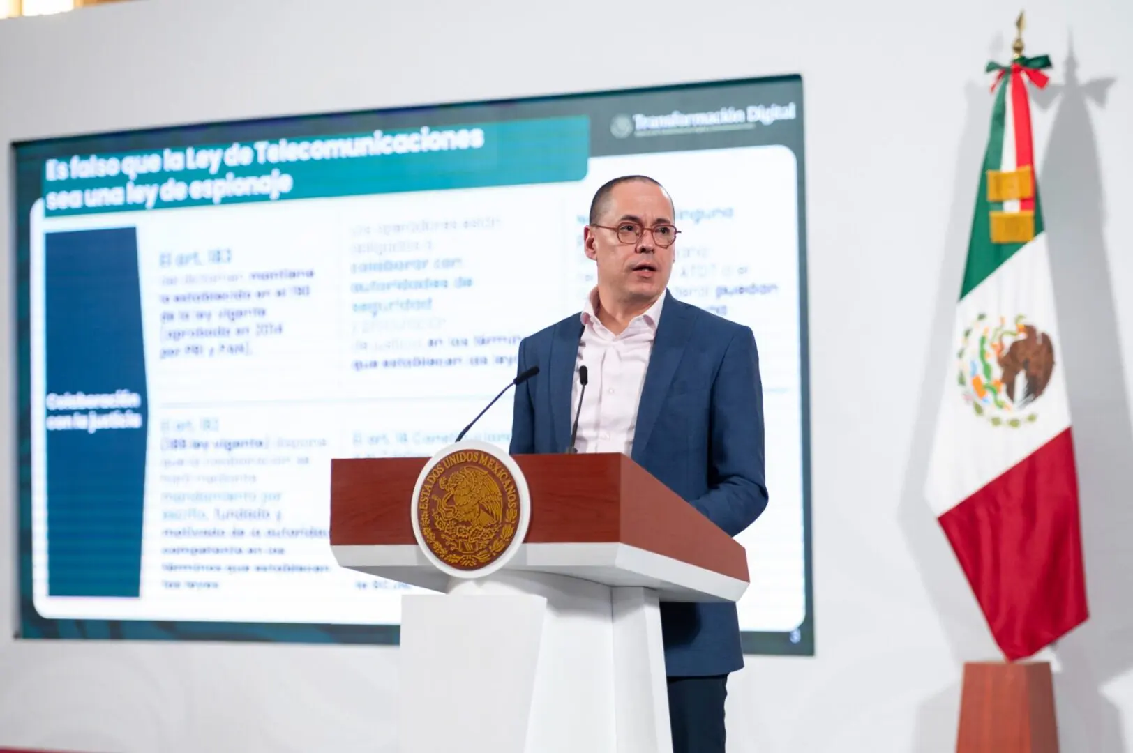 Man speaking at podium with Mexican flag