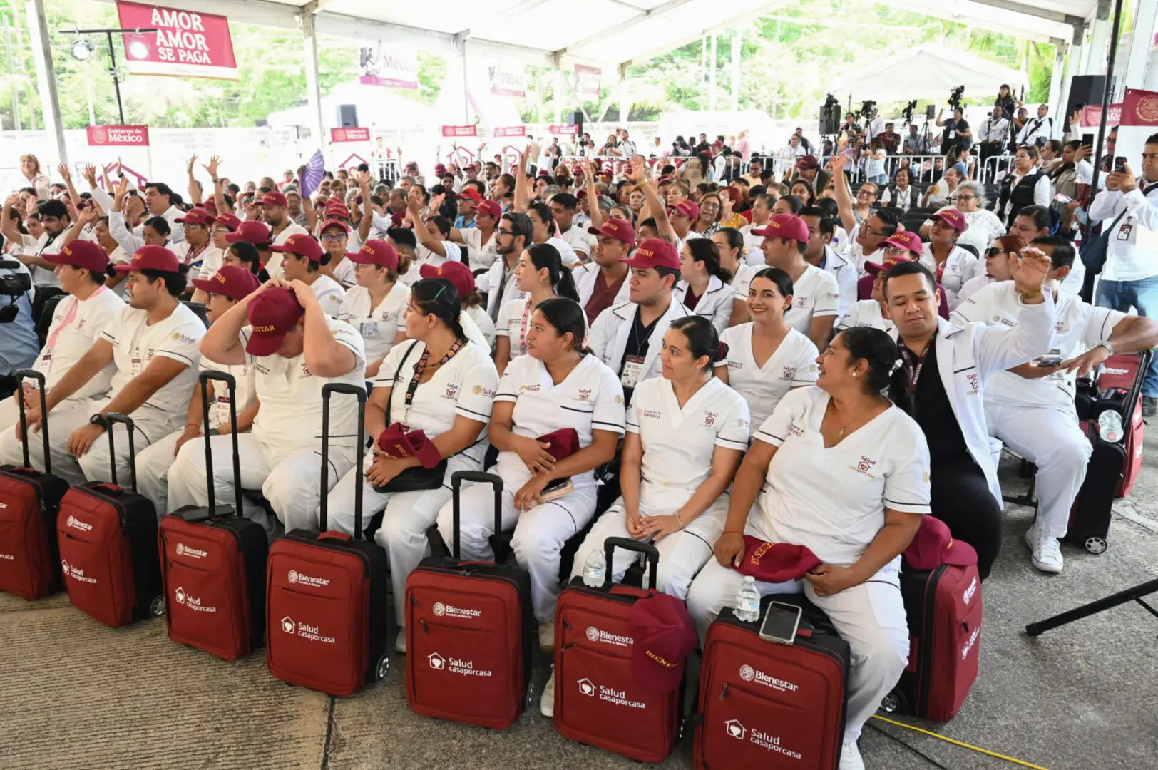 Group of healthcare workers with luggage seated.