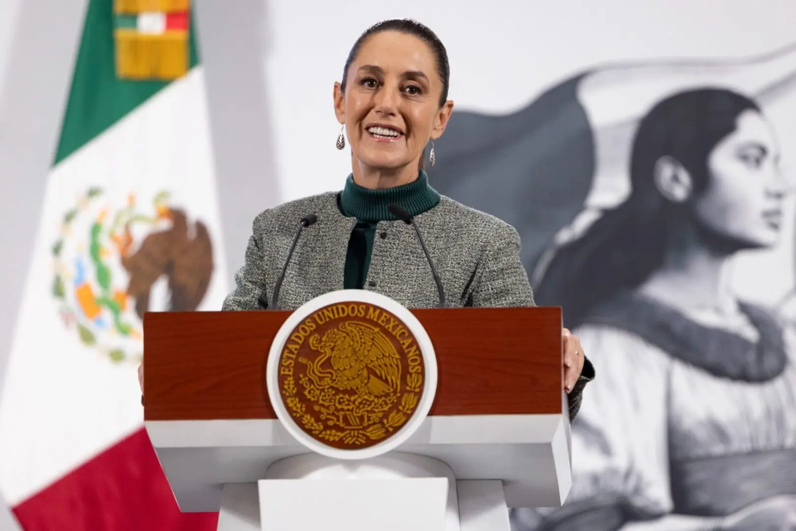 Woman speaking at Mexican podium with flag