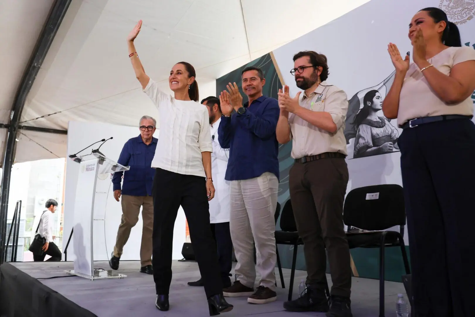La presidenta Claudia Sheinbaum saluda al público durante la inauguración del Hospital Pediátrico IMSS Bienestar en Culiacán, Sinaloa, acompañada por el gobernador Rubén Rocha y funcionarios del sector salud