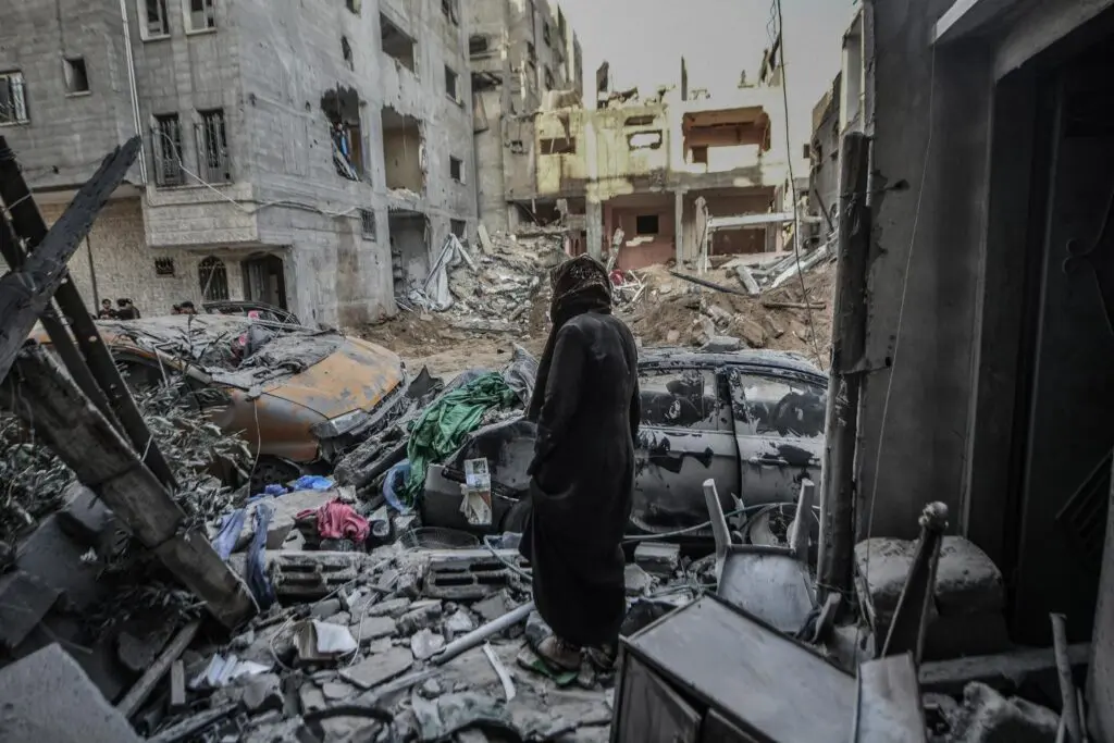 Persona entre escombros y edificios destruidos en Gaza tras bombardeos.