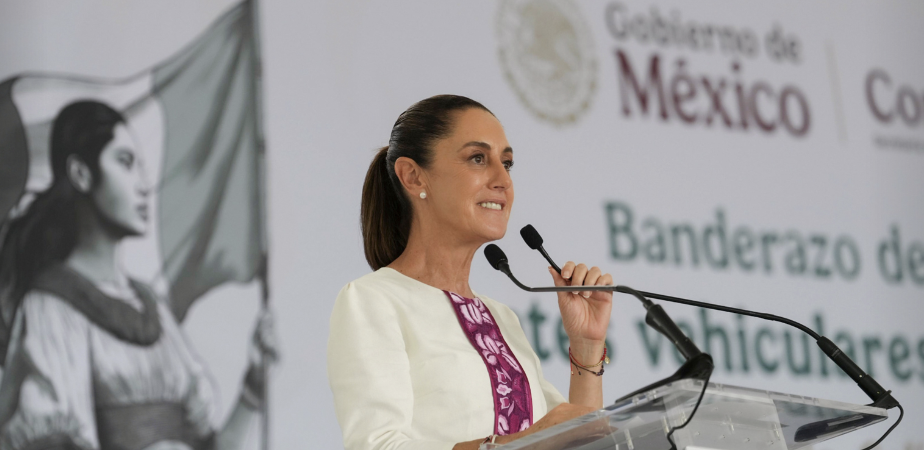 Woman speaking at podium with Mexico backdrop