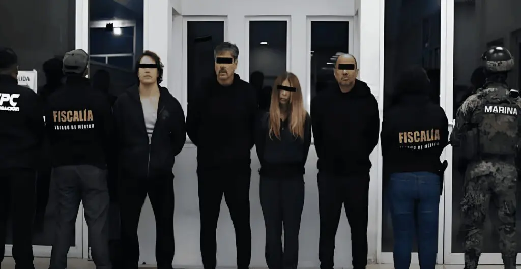 Law enforcement officials and detainees lined against wall