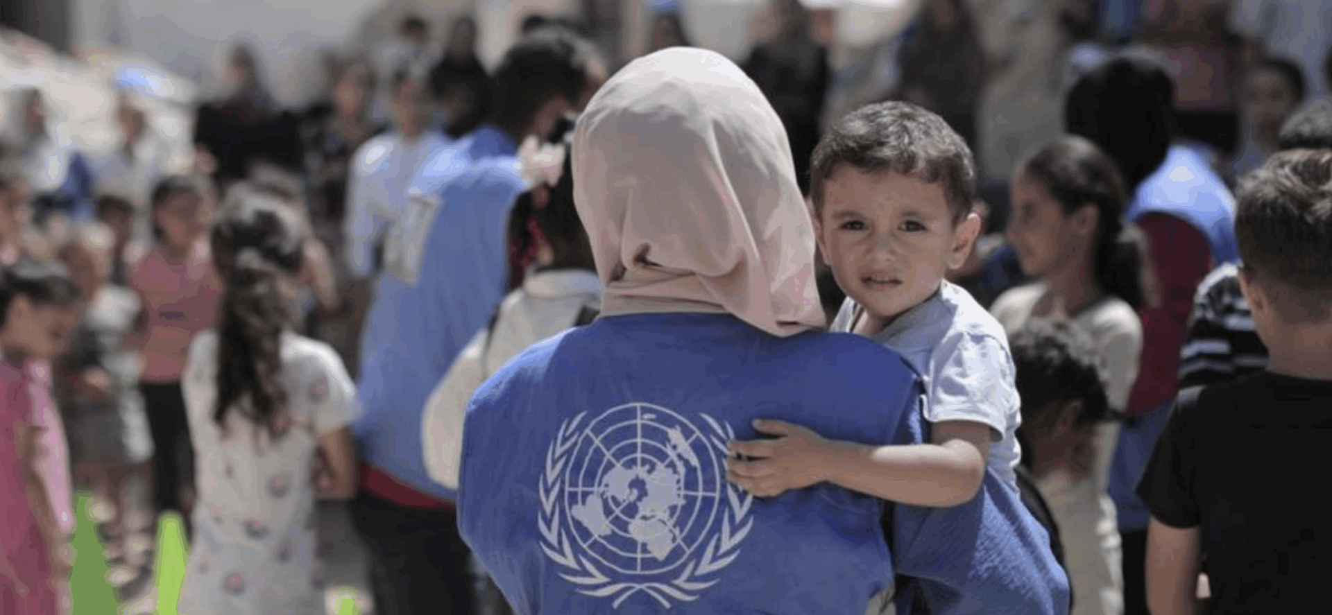 Trabajadora de la ONU sostiene a un niño en Gaza