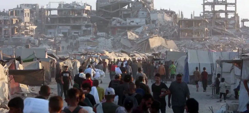 Personas caminan entre edificios dañados en Gaza tras ataques