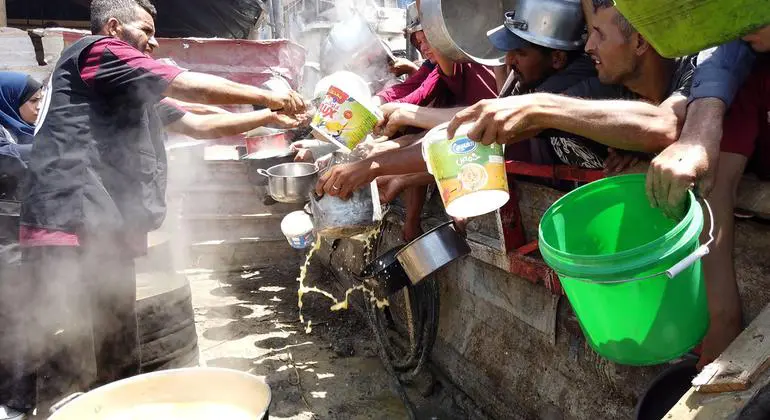 Voluntarios reparten comida a personas con cubetas y ollas en Gaza