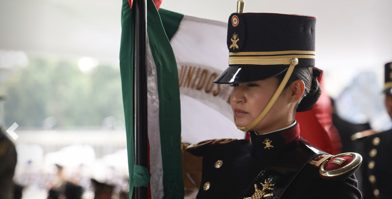 Mujer cadete mexicana en ceremonia militar con bandera nacional
