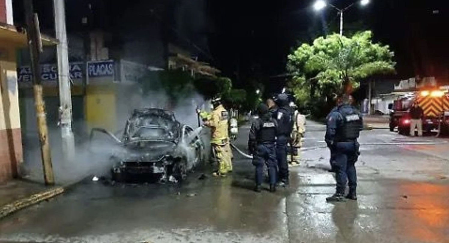 Firefighters extinguishing burning car at night.