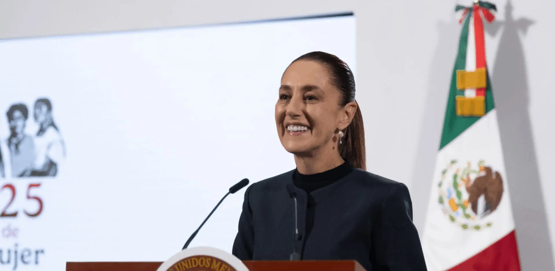 Smiling speaker at podium with Mexican flag