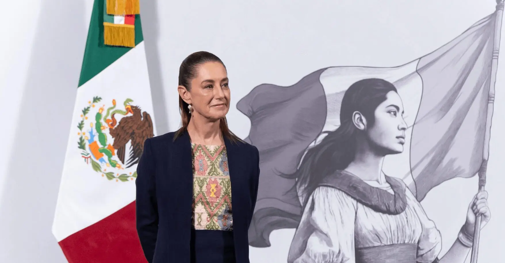 Woman standing by Mexican flag and mural