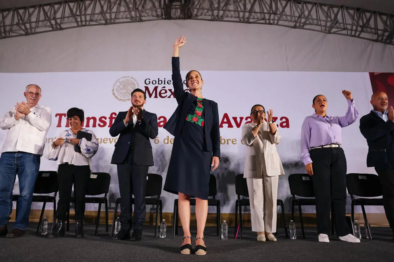 Woman waving on stage with applauding officials