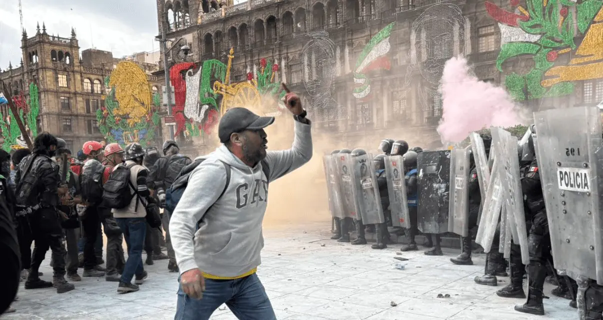 Protester confronting police with shields, smoke present.