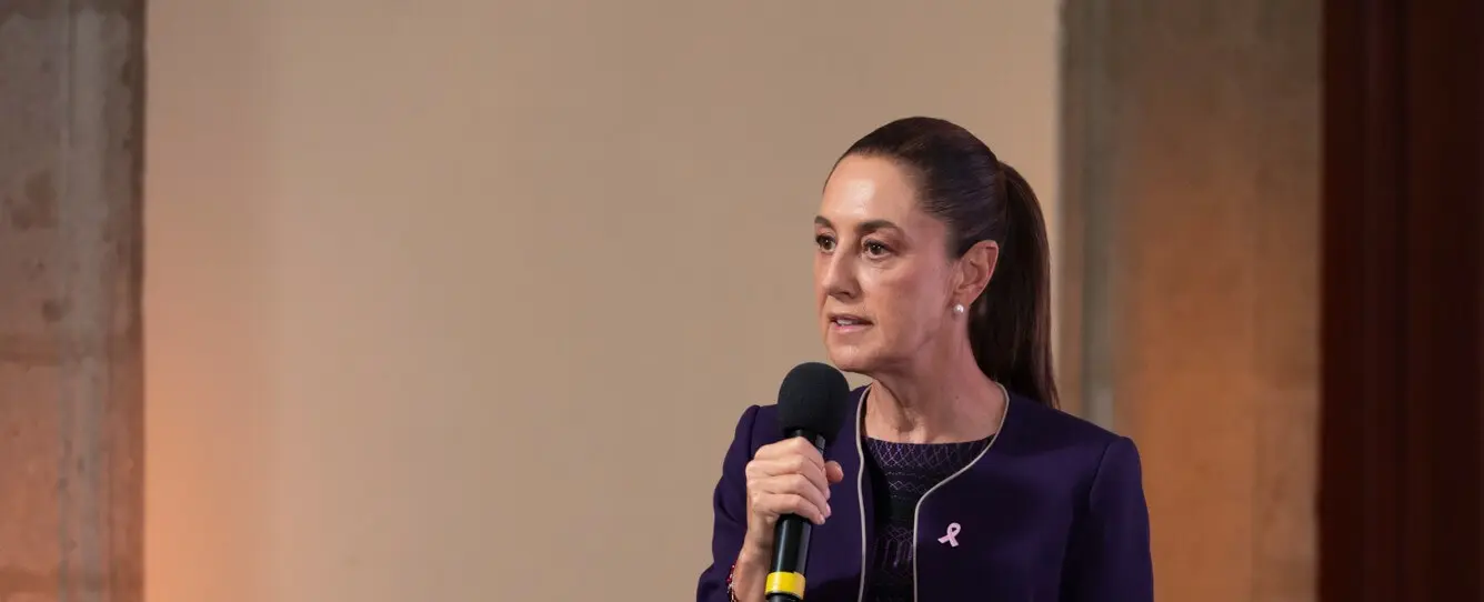 Woman speaking into microphone wearing purple blazer