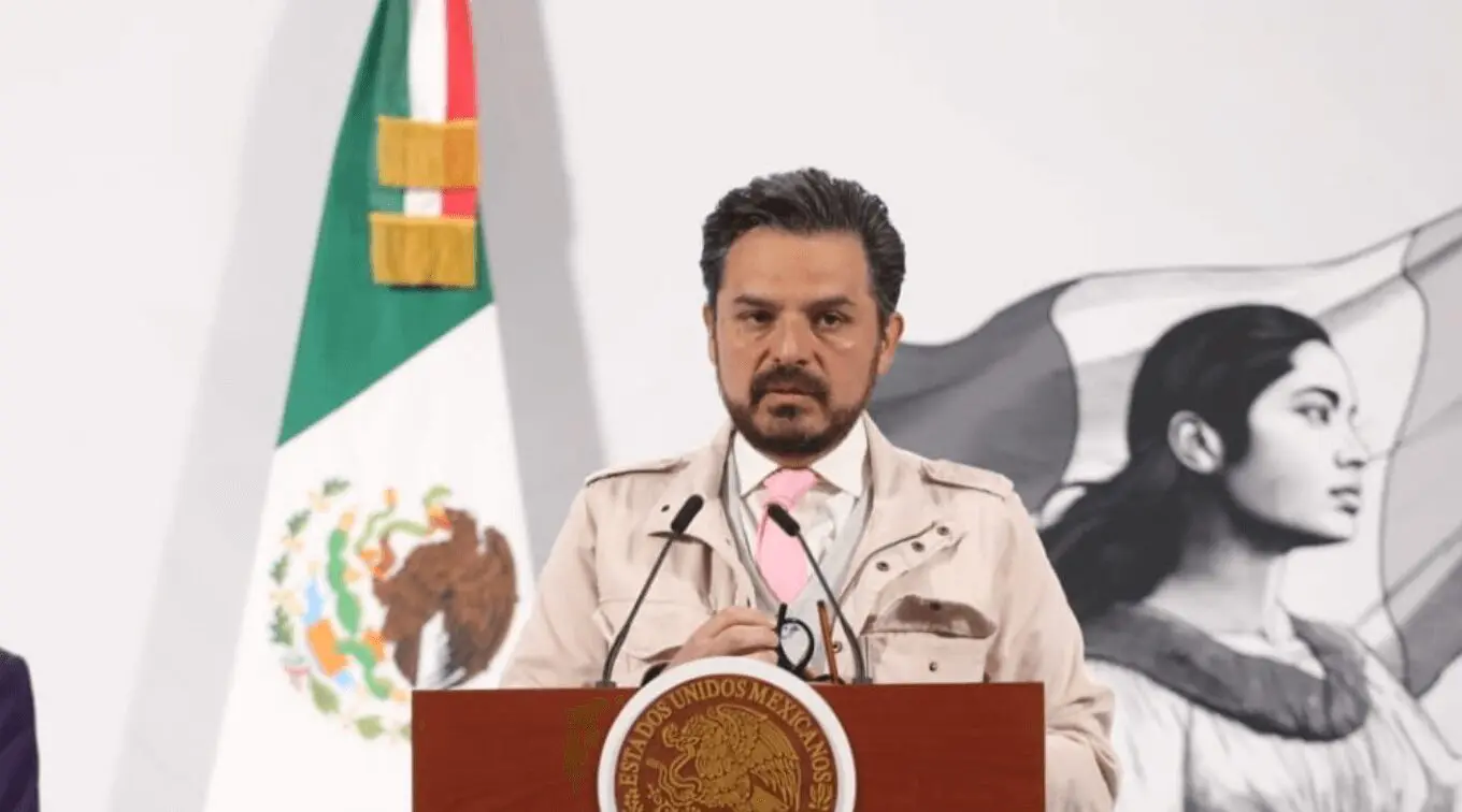 Man speaking at podium with Mexican flag