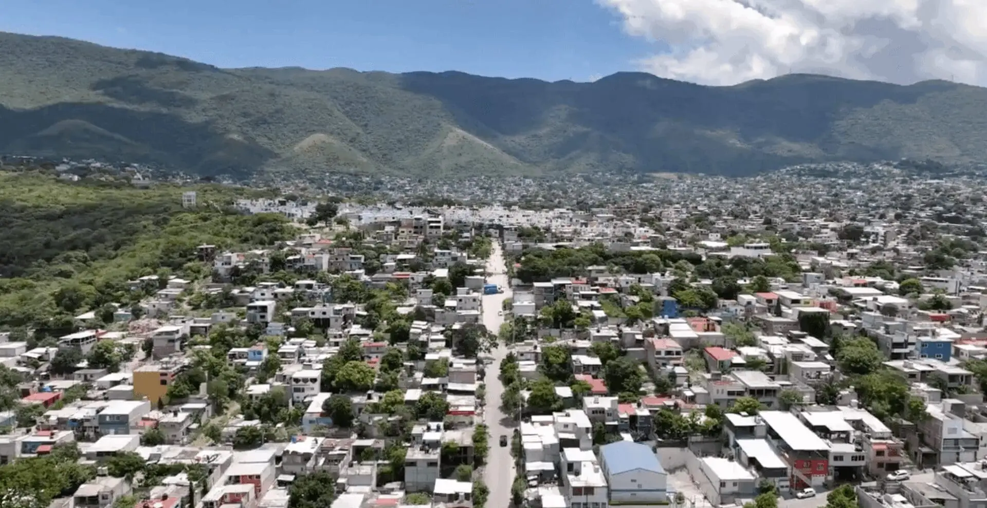 Cityscape with mountains and cloudy sky.