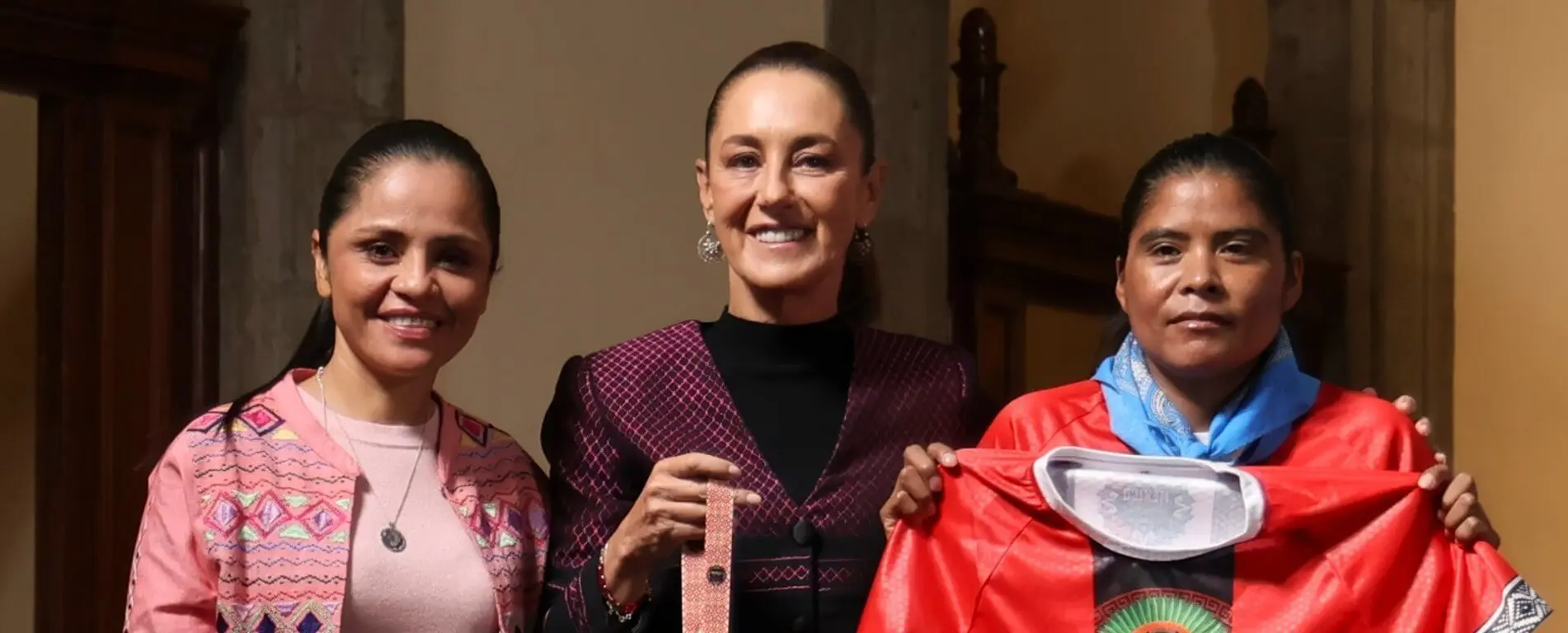 Three smiling women displaying colorful traditional garments