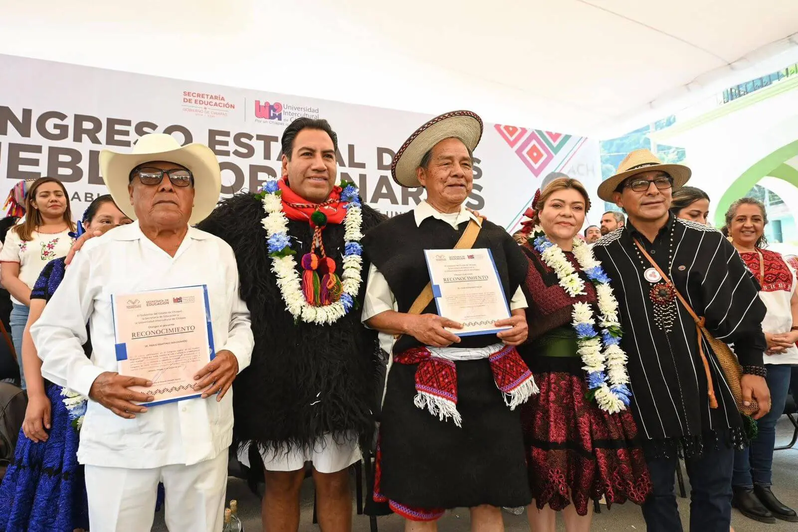 Group in traditional attire holding certificates