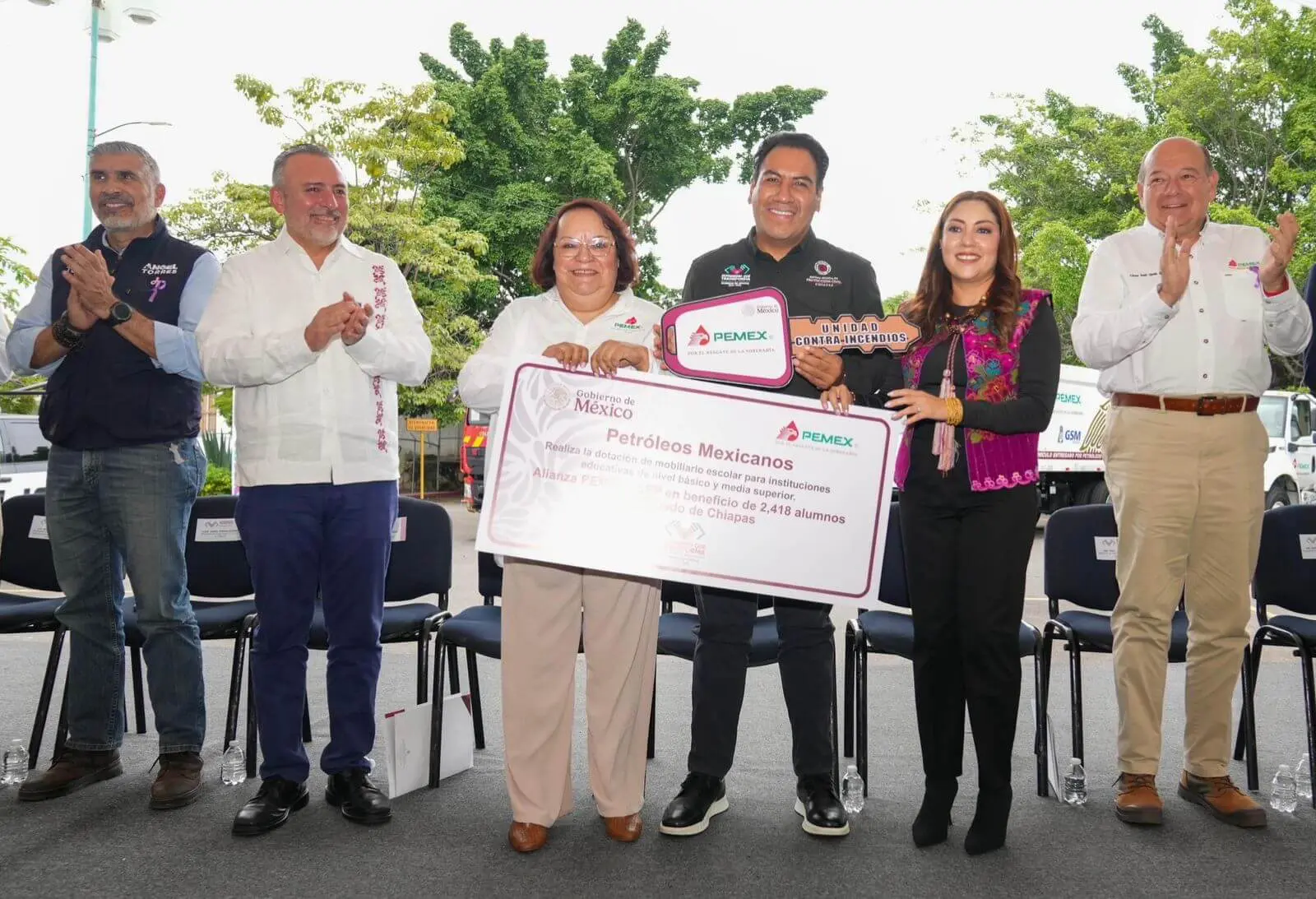 Officials holding large ceremonial check at event