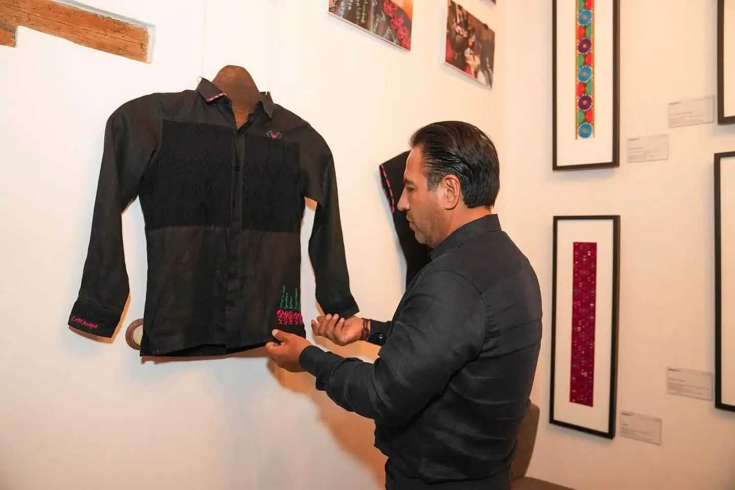 Visitor adjusts black embroidered shirt in gallery
