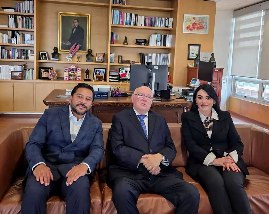 Three people sitting on a brown couch.