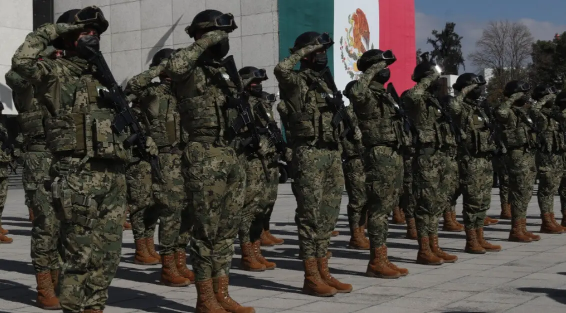 Row of saluting soldiers with Mexican flag
