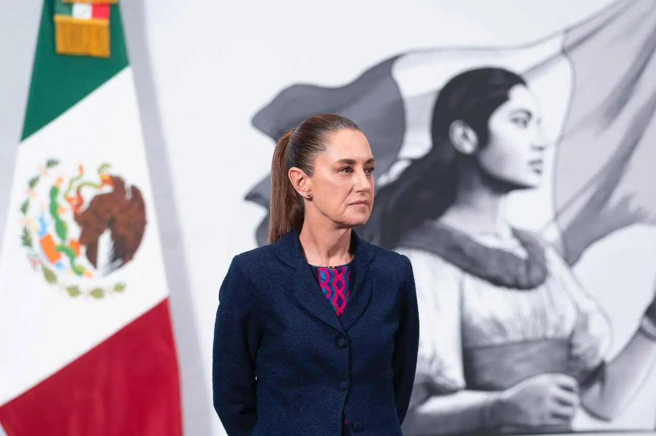 Woman standing before Mexican flag and mural