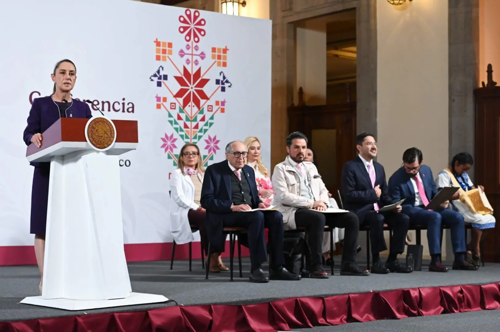 Woman speaking at podium before seated officials