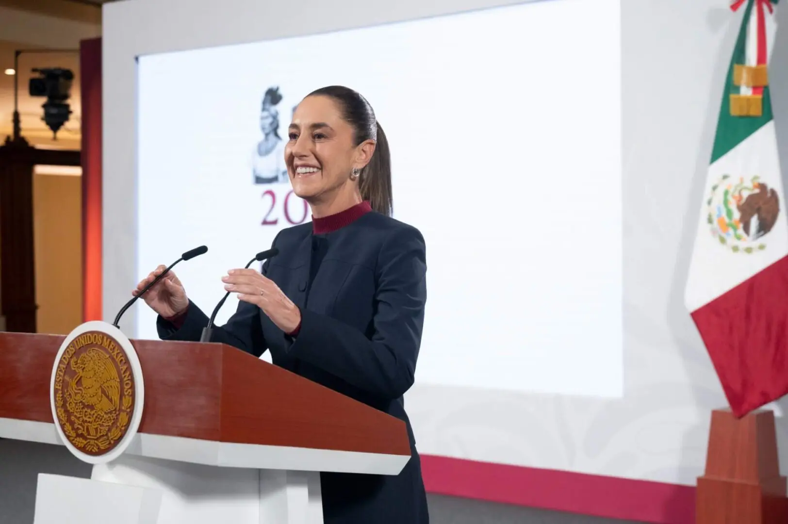 Smiling woman at podium with Mexican flag
