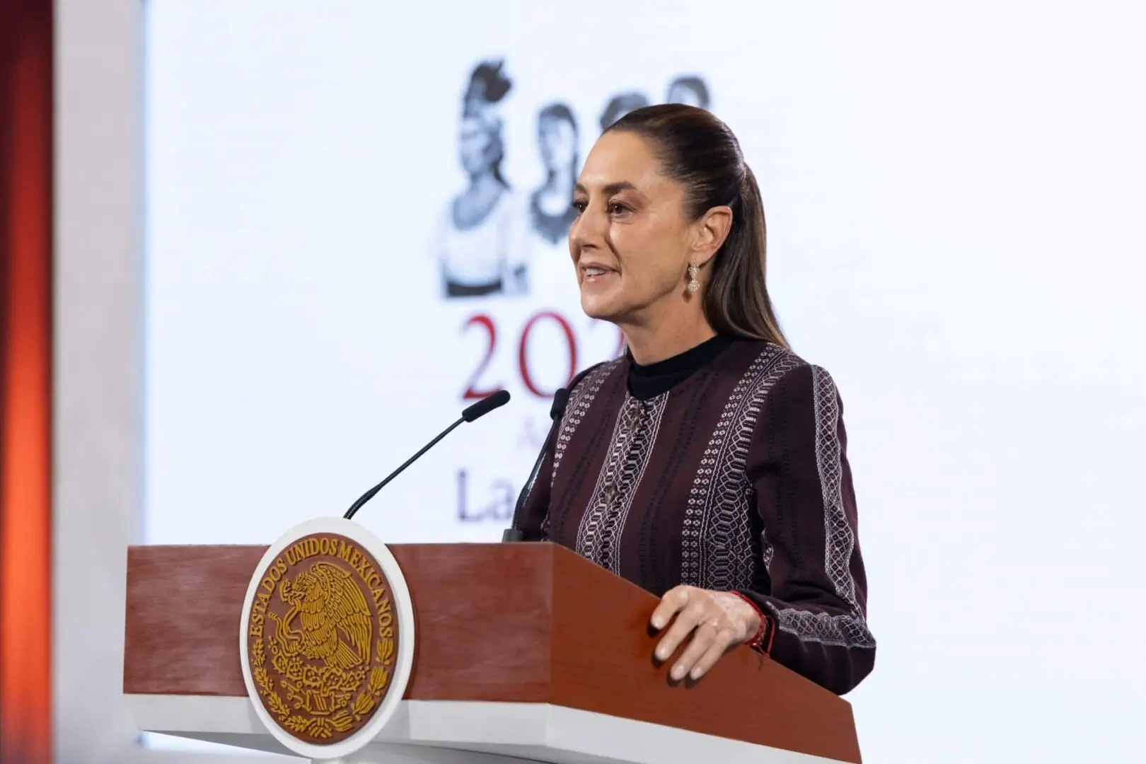 Woman speaking at podium with Mexican seal