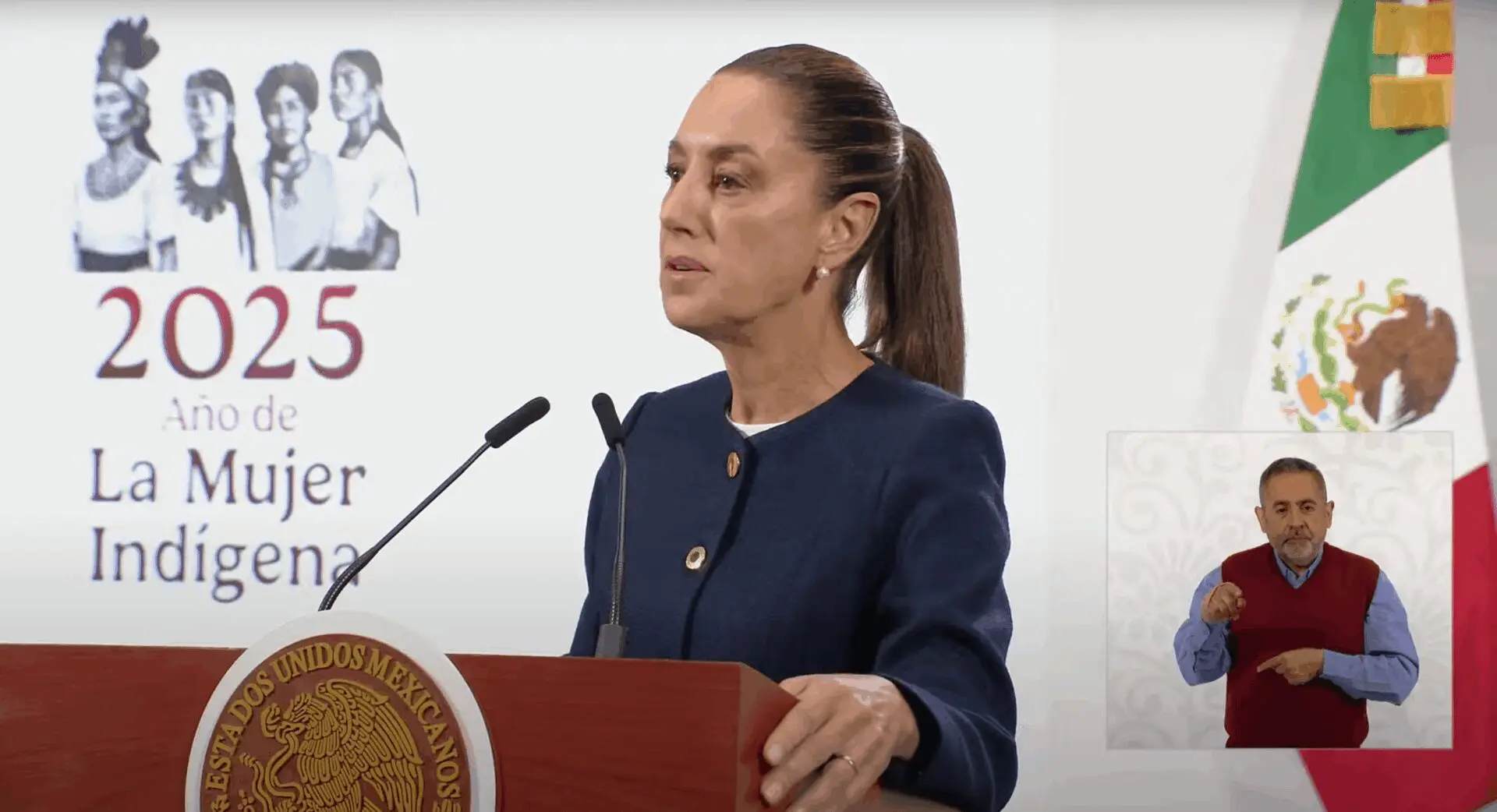Woman speaking at podium, sign language interpreter nearby