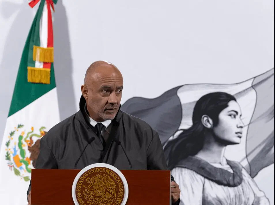 Speaker at podium with Mexican flag backdrop