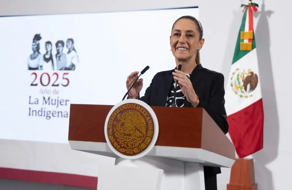 Woman speaking at podium with Mexican flag